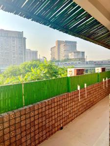 新德里House Of Comfort Delhi的城市中带绿色围栏的砖墙