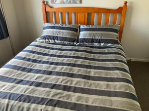 陶波Large stand alone home with two living areas.的一张带蓝色和白色条纹床单和枕头的床