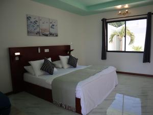 甘岛Clouds Beach Retreat Laamu Gan的卧室配有带枕头的床铺和窗户。