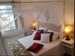 马卡埃Flat Bela Vista的卧室配有带红色枕头的白色床