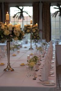 斯托桥达恩斯雷大厅酒店的一张长长的白色桌子,上面有蜡烛和鲜花