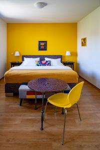 米库洛夫格列佛公寓酒店的一间卧室配有床和桌子,还有黄色的墙壁