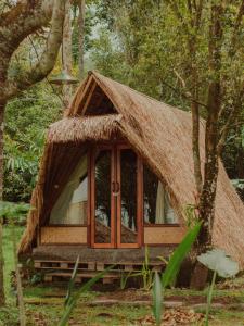姆杜克Da'kayu Glamping的树林中带茅草屋顶的小小屋