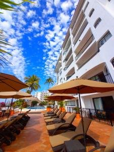 巴亚尔塔港One Beach Street Puerto Vallarta的一座建筑旁的带椅子和遮阳伞的酒店