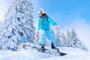 阿贝托内Residenza Riva Wellness Apartment Spa的一名妇女沿着雪覆盖的斜坡骑滑雪板