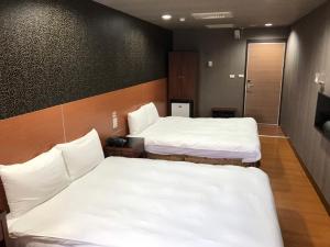 高雄龙翔商务大饭店的配有白色床单的客房内的两张床