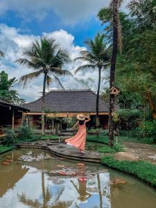 乌布Korurua Dijiwa Ubud的站在池塘前戴帽子的妇女