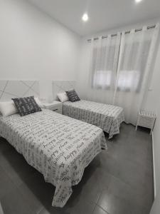 帕洛斯德拉夫龙特拉Excelente piso con aparcamiento privado的配有2张床的白色墙壁和窗户客房