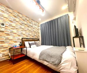 东京tani house的一间卧室设有一张床和砖墙