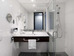 维尔纽斯立陶宛丽笙布鲁酒店 的白色的浴室设有水槽和淋浴。