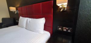 坎伯恩约翰弗朗西斯巴塞特韦瑟斯彭酒店的一间卧室配有一张红色床头板的床