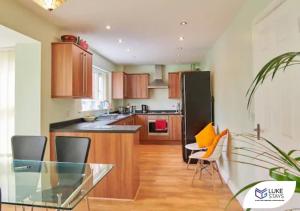 West CornforthLuke Stays - The Green的厨房配有玻璃桌和黑色冰箱。