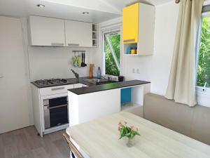 马佐Casitas Mobil Home的厨房配有白色橱柜和鲜花桌