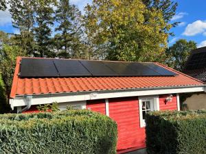 普劳西Blockbohlenhaus Plau am See的屋顶上设有太阳能电池板的红色房子