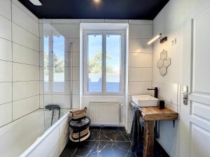 日安Appart LA MANUFACTURE - Maison 1911 - confort & prestige的带浴缸、水槽和窗户的浴室