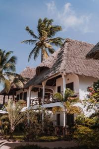 江比阿蓝牡蛎酒店的一座带茅草屋顶和棕榈树的建筑