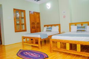 Stone TownZanzibar Spice Nest Apartment的卧室配有两张床,地板上铺有地毯。
