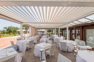 费拉约港Hotel Airone isola d'Elba的庭院里的餐厅配有白色的桌椅