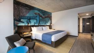 塔尔萨Hotel Indigo Tulsa DWTN/Entertainment Area的酒店客房设有一张床,墙上挂有绘画作品