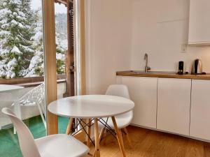 巴特维塞Apartmenthaus am Tegernsee - Studios mit Küchenzeile und mit Bus erreichbar的厨房配有白色的桌椅和窗户。