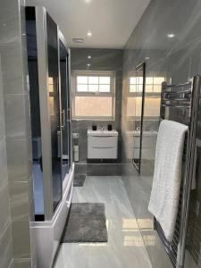埃奇韦尔2 Double Bedroom Apartment in Edgware, London的浴室配有水槽、淋浴和水槽Kor M Hbestosbestos