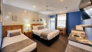 扬Colonial Motel & Apartments的酒店客房配有两张床和一张书桌