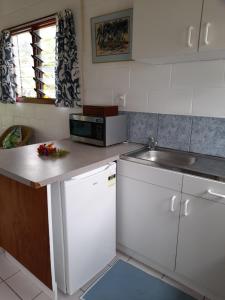 拉罗汤加Reefcomber Sunset Beach的厨房配有白色橱柜、水槽和柜台。