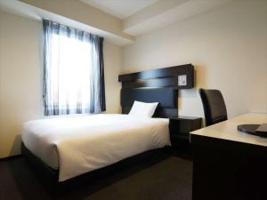 池田Green Rich Hotel Osaka Airport的一间卧室配有一张床、一个窗口和一张书桌