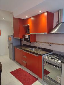 拉法尔达9 ¾ Apartamentos VIP的厨房配有红色橱柜、水槽和炉灶。
