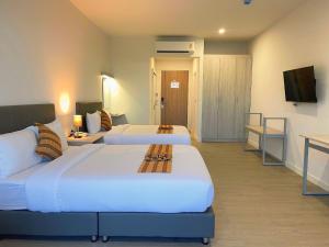 南奔GRAND PA Hotel&Resort Lamphun Chiang Mai的酒店客房设有两张床和电视。
