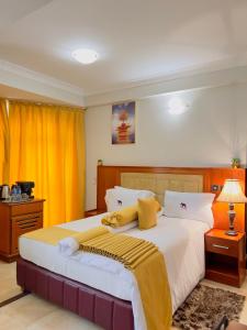 姆万扎LEYSHOF HOTEL的一间卧室配有一张带黄色窗帘的大床
