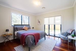 卢拉Alleura House Serene Bushland 4BR Families Groups的一间卧室配有一张床、一把椅子和窗户。