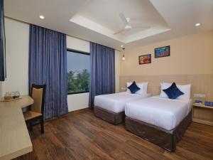钦奈Essentia Premier Hotel Chennai OMR的酒店客房配有两张床和一张书桌