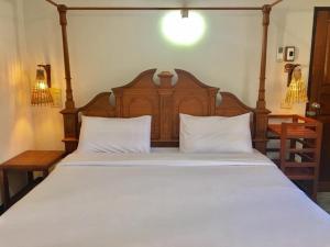 湄宏颂The Creek Garden Resort Huainamrin ห้วยนำ้ริน的卧室配有一张白色大床和木制床头板