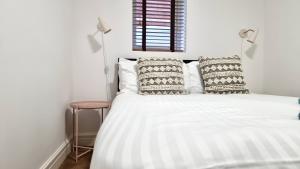 卡迪夫Thompson Apartments by Switchback Stays的卧室配有带枕头的白色床和窗户。
