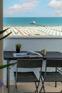 里米尼皮卡迪利酒店的一张桌子和椅子,配有一本书,享有海滩美景