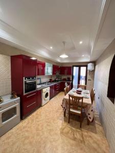 马拉喀什Superbe appartement avec parking gratuit的厨房配有红色橱柜和桌椅