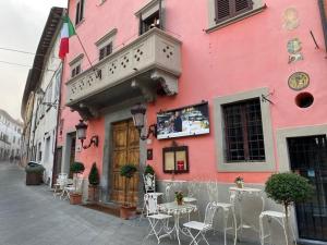 蒙托波利因瓦尔达尔诺Quattro Gigli Palace的街道上一座粉红色的建筑,配有桌椅