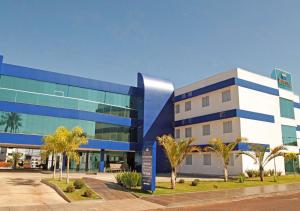 ItuiutabaBernal Hotel Econômico的一座蓝白色的建筑,前面有棕榈树