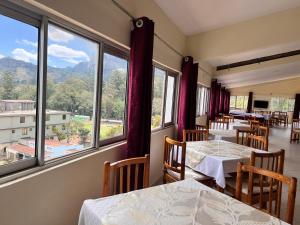 TsavoLavender Garden Hotel的餐厅设有桌椅和大窗户。