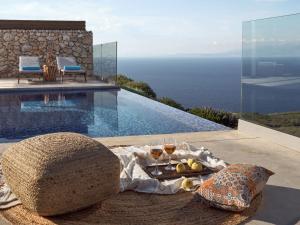 KoríthionAkron Luxury Suites的一张桌子,上面有酒杯和泳池旁的食品托盘