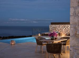 KoríthionAkron Luxury Suites的一个带桌椅的庭院和一个游泳池