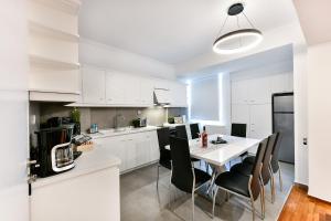 塞萨洛尼基Porto Sea View Apartments - Pl Ippodromiou 21的厨房配有白色橱柜和白色的桌椅