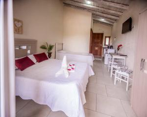普腊亚罗萨Pousada do Mica的一间卧室配有两张床和一张桌子及椅子