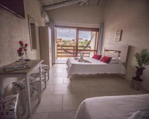 普腊亚罗萨Pousada do Mica的客房设有两张床、一张桌子和一扇窗户。
