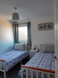 布里克瑟姆The Getaway - Modern 2 Bedroom Brixham Bungalow with sea peeps的一间卧室设有两张单人床和一个窗户。