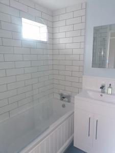 布里克瑟姆The Getaway - Modern 2 Bedroom Brixham Bungalow with sea peeps的白色的浴室设有浴缸和水槽。