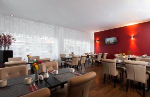美因河畔法兰克福法兰克福市中心莱昂纳多酒店的一间带桌椅和红色墙壁的餐厅