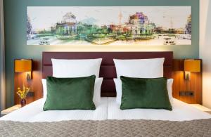 柏林柏林亚历山大广场莱昂纳多皇家酒店的一间卧室配有一张带两个绿色枕头的床