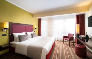 柏林柏灵莱昂纳多酒店的酒店客房设有一张大床和一张红色椅子。